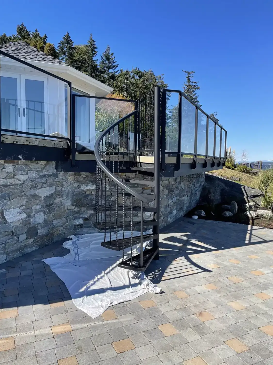 Spiral stair against a stone wall with the ocean behind